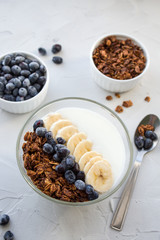 delicious breakfast. Homemade granola with honeysuckle berries, banana and yogurt in a Cup on a grey background. copy space. Top view.