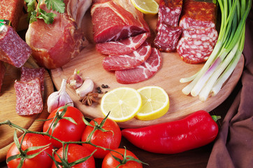 Ham, sausage and vegetables on the kitchen board