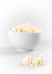 Bowl of fresh popcorn with a few popcorn in front focus on isolated