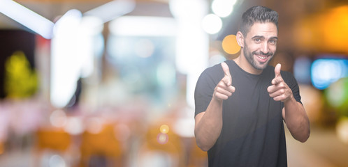 Young handsome man over isolated background pointing fingers to camera with happy and funny face. Good energy and vibes.