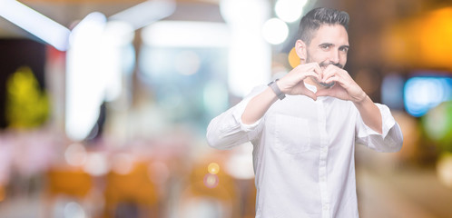 Young business man over isolated background smiling in love showing heart symbol and shape with hands. Romantic concept.