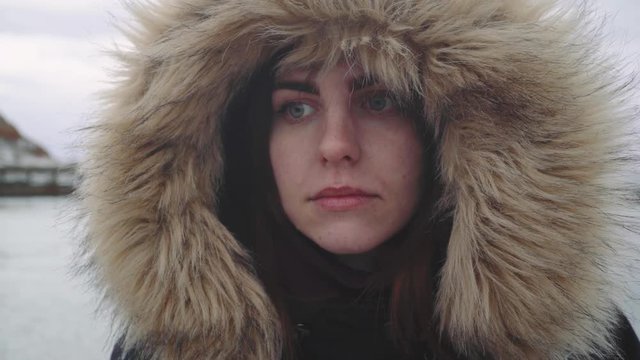 Closeup portrait of a young beautiful red-haired woman outdoors. Girl in a warm fluffy jacket