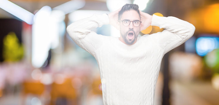 Young handsome man wearing glasses over isolated background Crazy and scared with hands on head, afraid and surprised of shock with open mouth