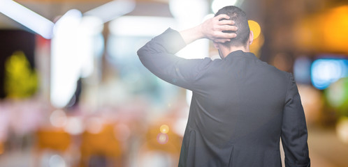 Young Christian priest over isolated background Backwards thinking about doubt with hand on head