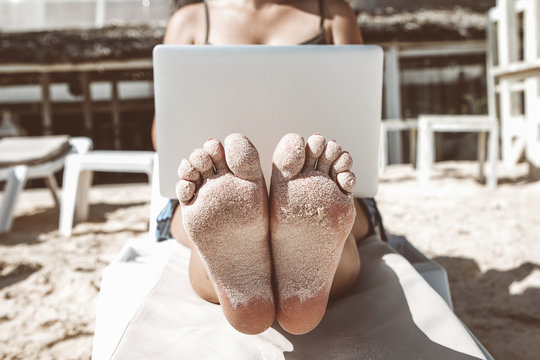 Happy freelance woman on sunbad working on laptop on the beach