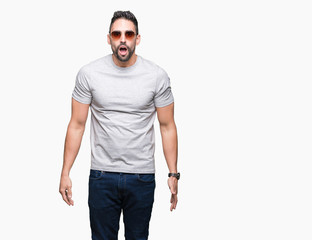 Young handsome man wearing sunglasses over isolated background afraid and shocked with surprise expression, fear and excited face.