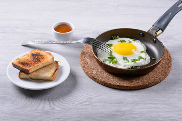 fried eggs on a frying pan, toast and sauce