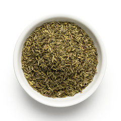 Dried rubbed thyme in a white ceramic bowl isolated on white from above.