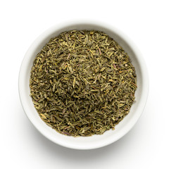 Dried rubbed thyme in a white ceramic bowl isolated on white from above.