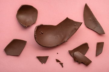 broken chocolate Easter egg over pink background, holiday concept