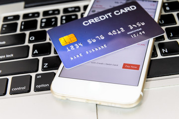 credit card put on mobile phone and laptop keyboard for preparing to pay online shopping