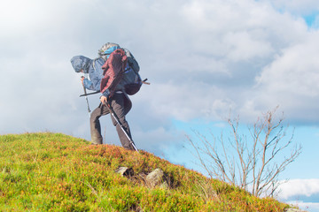A woman with a backpack on a hike climbs the mountain.