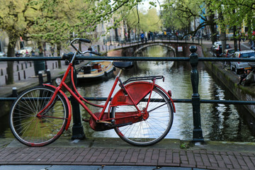 Fototapeta na wymiar A picture of a lonely red bike on the bridge over the channel in Amsterdam.