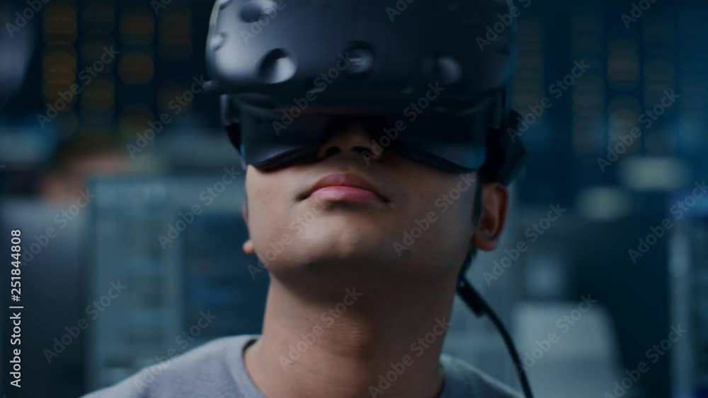 Fototapete Software Delevoper Wearing Virtual Reality Headset Gesturing with His Head, Developing and Programming VR Game or Application. In Background Technology Developing Studio with Computers and Monitors