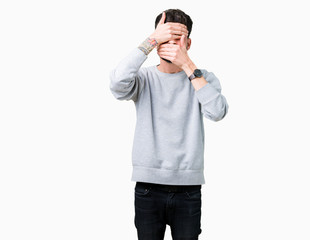 Young handsome man wearing sweatshirt over isolated background Covering eyes and mouth with hands, surprised and shocked. Hiding emotion