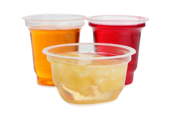 Jam in plastic cups with raw fruit on white background