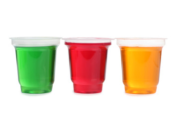 Jam in plastic cups with raw fruit on white background