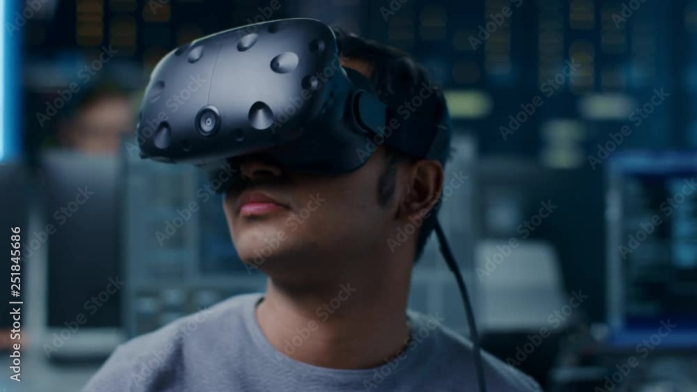 Aufkleber Software Delevoper Wearing Virtual Reality Headset Gesturing with His Head, Developing and Programming VR Game or Application. In Background Technology Developing Studio with Computers and Monitors