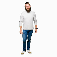 Young blond man wearing casual sweater winking looking at the camera with sexy expression, cheerful...