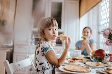 Portrait of girl eating pancake at table