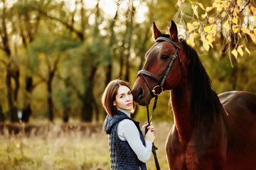 Fototapeta premium Woman with her horse at sunset, autumn outdoors scene