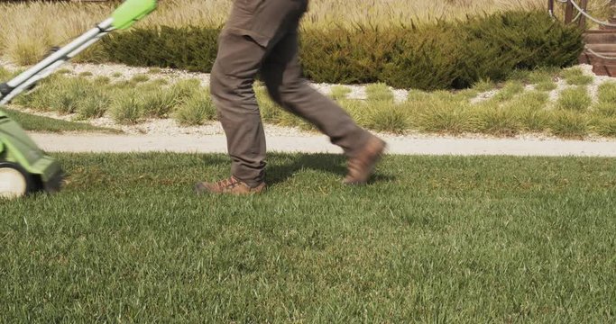 Gardener operating scarifying machine in grass lawn