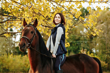 Fototapeta premium Beautiful girl riding a horse on autumn field