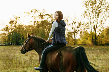 Beautiful girl riding a horse on autumn field