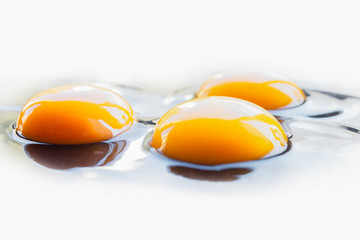Three fresh raw chicken eggs spilled on a light background	