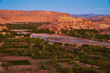 Wide shot of Ait Ben Haddou historic popular touristic town and the green oasis around the river