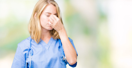 Beautiful young doctor woman wearing medical uniform over isolated background tired rubbing nose and eyes feeling fatigue and headache. Stress and frustration concept.