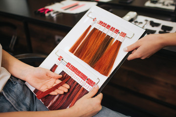 Hair color chart at salon. Female client with hairdresser choosing color hair from palette samples before coloring