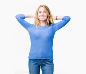 Fototapeta premium Beautiful young woman wearing blue sweater over isolated background Relaxing and stretching with arms and hands behind head and neck, smiling happy