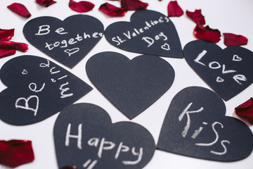 Black valentines with love text, carved from a cloth on a white background with rose petals