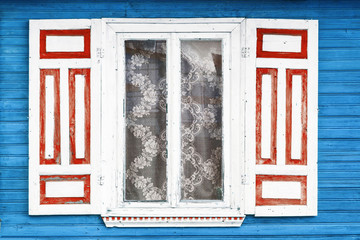 Fototapeta premium Wooden rustic window in small cottage house. Vintage wall with transparent glass window and decorative red and white shutter.