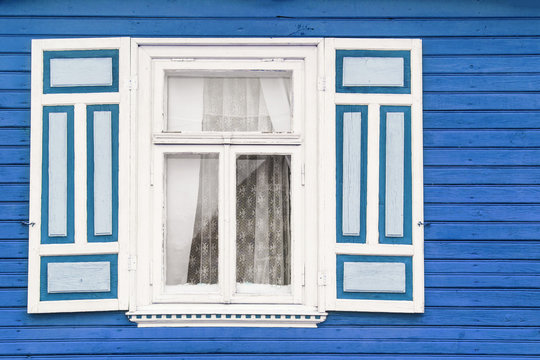 Wooden rustic window in small cottage house. Vintage blue paint wall with transparent glass window and decorative white shutter.