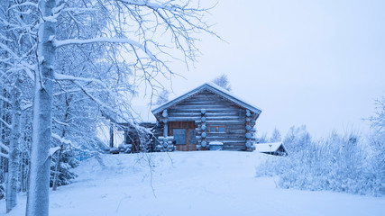 Winter landscape trees and wooden log house. Traditional Finnish buildings.  Finland Lapland mountain slope. Panorama