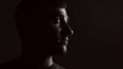 portrait of a guy on a black background in low key