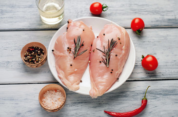 Raw chicken breast fillets ready for cooking on a wooden cutting board with spices. on a wooden...