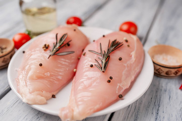 Raw chicken breast fillets ready for cooking on a wooden cutting board with spices. on a wooden...