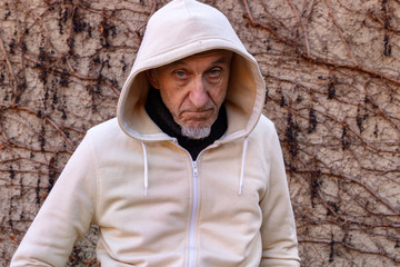 Portrait of senior man in hood in front of a wall