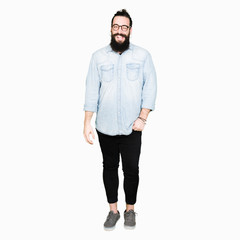 Naklejka premium Young hipster man with long hair and beard wearing glasses winking looking at the camera with sexy expression, cheerful and happy face.