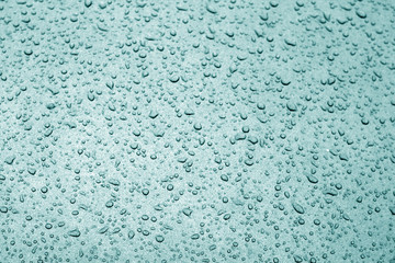 Fototapeta na wymiar Water drops on car surface in cyan tone.