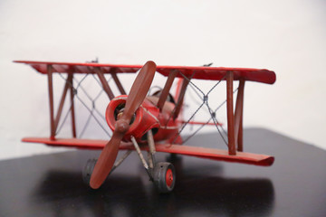 model of a red biplane aircraft with propeller driven engine on a black desk in front of white background isolated © Sylvia