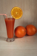 Oranges and a glass of juice on a wooden background.