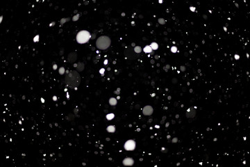Snowstorm texture. Bokeh lights on black background, shot of flying snowflakes in the air