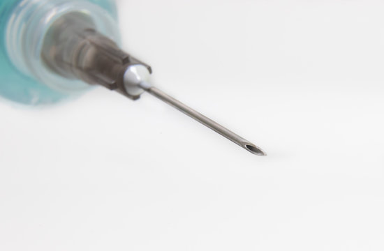 macro photo of a syringe with needle and a liquid inside, in close up.