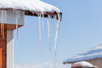 Icicle melts with falling drops on a background of bright blue sky