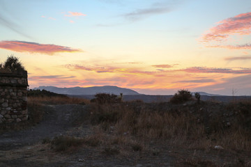 sunset over the mountains in a steppe region with dry grass and colorful sky