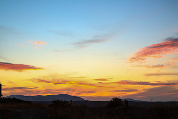 Fototapeta na wymiar all colors colours orange red purple blue sunset sky over hilly landscape steppe